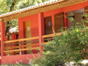 uma casa vermelha com uma cerca em frente em Camping Parc Saint Sauvayre em Vagnas