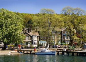 a sailboat is docked at a dock in front of houses at The Waterhead Inn- The Inn Collection Group in Ambleside