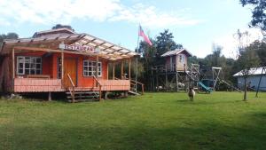 un edificio in un campo con una casa di Cabanas Neptuno a Quellón