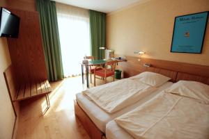 a bedroom with two beds and a table and a television at An der Persiluhr Stadt-gut-Hotel in Lünen