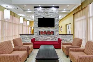 a waiting room with a red couch and a tv at Best Western Plus Bowmanville in Bowmanville