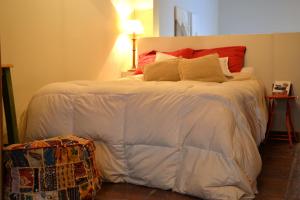um quarto com uma cama grande com lençóis brancos e almofadas vermelhas em Loft Urbano em Tandil