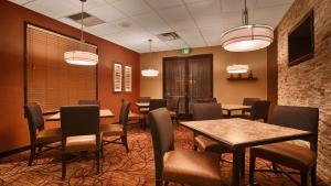 uma sala de jantar com mesas, cadeiras e luzes em Hotel d'Lins Ontario Airport em Ontario