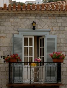 ventana con 2 macetas de flores en el balcón en Guesthouse Corali en Hydra