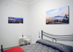 sypialnia z łóżkiem i dwoma obrazami na ścianie w obiekcie Obelisco w mieście Napoli