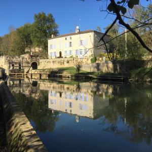 una casa sentada junto a un río con un edificio en Moulin de Bapaumes, en Nérac