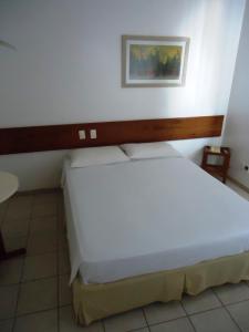 um quarto com uma grande cama branca num quarto em Bravo City Rondonópolis em Rondonópolis