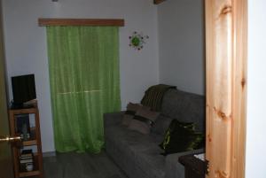uma sala de estar com um sofá e uma cortina verde em Cantinho do mar em Urzelina