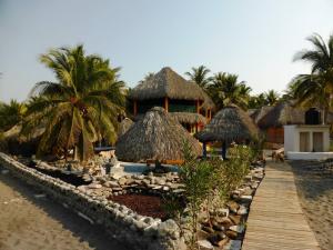 Eco-Hotel Playa Quilombo في Las Lisas: منتجع على الشاطئ فيه نخل وممشى خشبي