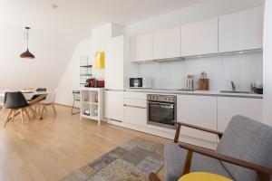 kuchnia z białymi szafkami i stołem z krzesłami w obiekcie Mar Suite Apartments - Center w Wiedniu