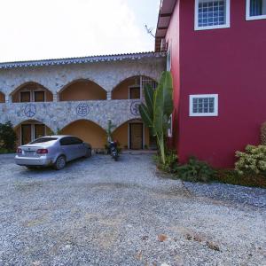 un coche aparcado frente a un edificio rojo en Pousada Casa de Pedra, en Boicucanga
