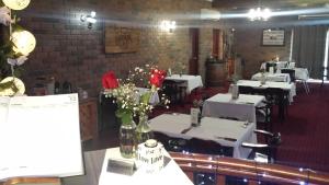 a dining room with white tables and flowers in vases at Cattleman's Rest Motor Inn in Charters Towers