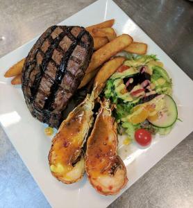 a plate of food with meat and potatoes and vegetables at Cattleman's Rest Motor Inn in Charters Towers