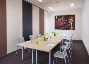 a room with tables and chairs and a painting on the wall at Citadines on Bourke Melbourne in Melbourne