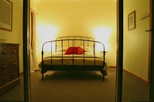 a bedroom with a bed with red pillows and a mirror at Butterworth Cottage in Castlemaine
