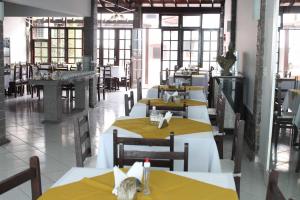 a restaurant with tables and chairs with yellow tables at Hotel Pousada da Néia in Cananéia