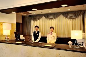 Dos hombres están parados en una recepción. en Grand Park Hotel Panex Kimitsu, en Kimitsu