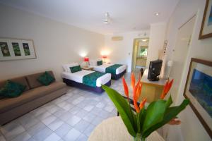 una camera d'albergo con due letti e un divano di Lazy Lizard Motor Inn a Port Douglas