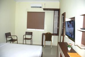 a room with a bed and chairs and a tv at Avon's Residence in Manado