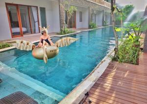 a woman sitting in an inflatable raft in a swimming pool at Mahana Living in Denpasar