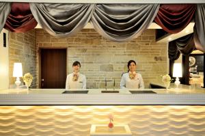 two people in white uniforms standing behind a desk at Grand Park Hotel Panex Tokyo in Tokyo