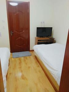 Habitación con 2 camas, TV y puerta en Xinming Fashion Hotel en Yanji