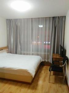 1 dormitorio con 1 cama y ventana con TV en Xinming Fashion Hotel en Yanji