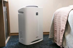 a white water heater sitting next to a bed at Grand Park Hotel Panex Tokyo in Tokyo