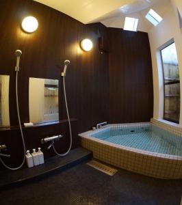 a bathroom with a jacuzzi tub with two showers at 赤川温泉スパージュ-Spaju in Taketa