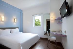 ein Hotelzimmer mit einem weißen Bett und einem TV in der Unterkunft Amaris Hotel Cimanuk Bandung in Bandung