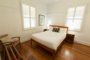 a white bedroom with a bed and two windows at Pooles Rock Vineyard Accommodation in Pokolbin