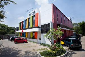 a building with cars parked in a parking lot at Amaris Hotel Cimanuk Bandung in Bandung