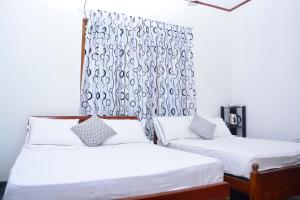 1 dormitorio con 2 camas y cortina en Livinginn Polonnaruwa, en Polonnaruwa