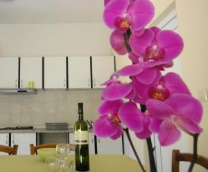 een fles wijn naast een tafel met paarse orchideeën bij House Riviera in Mošćenička Draga