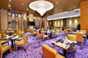 ein Restaurant mit Tischen, Stühlen und einem Kronleuchter in der Unterkunft Grand Skylight International Hotel Huizhou in Huizhou