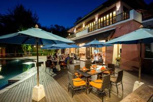 湄登的住宿－Sibsan Resort & Spa Maetaeng SHA，游泳池旁带桌子和遮阳伞的天井