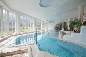 a large swimming pool in a building with windows at Alpenhotel Neuwirt in Schladming