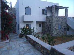 a white building with a stone wall next to a building at Summer dream , 5 min walk to the beach in Livadakia