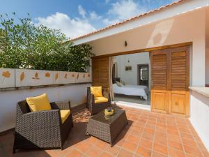 a patio with two chairs and a table and a bed at Kadal The Beach House in Puducherry