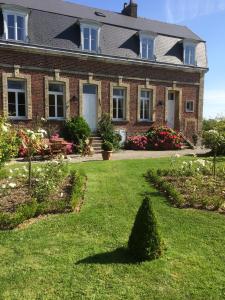 een groot bakstenen huis met een groene tuin bij Le Clos Boutenelle in Éperlecques