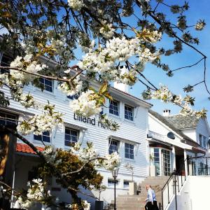 um homem andando em frente a um edifício branco com flores em Lilland Brewery Hotel em Tau