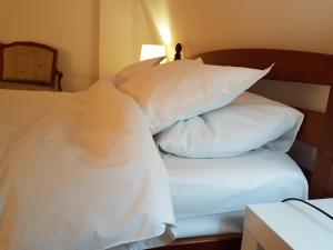 - un lit avec des oreillers blancs dans l'établissement Bucharest Boutique Accommodation by Hotels, à Bucarest