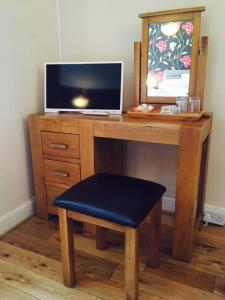 a wooden desk with a television and a stool at The Crown Hotel in Peebles