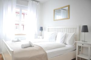 een witte slaapkamer met een wit bed en een spiegel bij Cozy Apartment Ulmenstrasse in Luzern