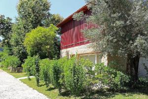 a building with a red roof next to a hedge at Recantos na Portela in Amares