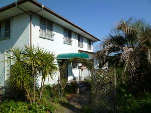 a white house with palm trees in front of it at Pension Flora in Tateyama