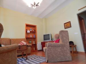 Casa Rural La Perra Gorda في Zorita: غرفة معيشة مع أريكة وكراسي وتلفزيون