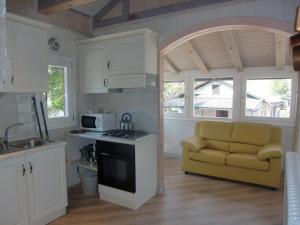 uma cozinha com armários brancos e um sofá amarelo em Casa Carla em Ledro