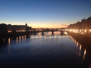 un puente sobre un río por la noche con luces en Residenza 54, en Florencia