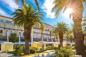 a courtyard with palm trees in front of a building at Royal Antique Apartment in Split